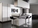 Here a pale colour palette is offset by dark tiles and other subtle accents, with appliances hidden from view behind tall elegant cabinetry.